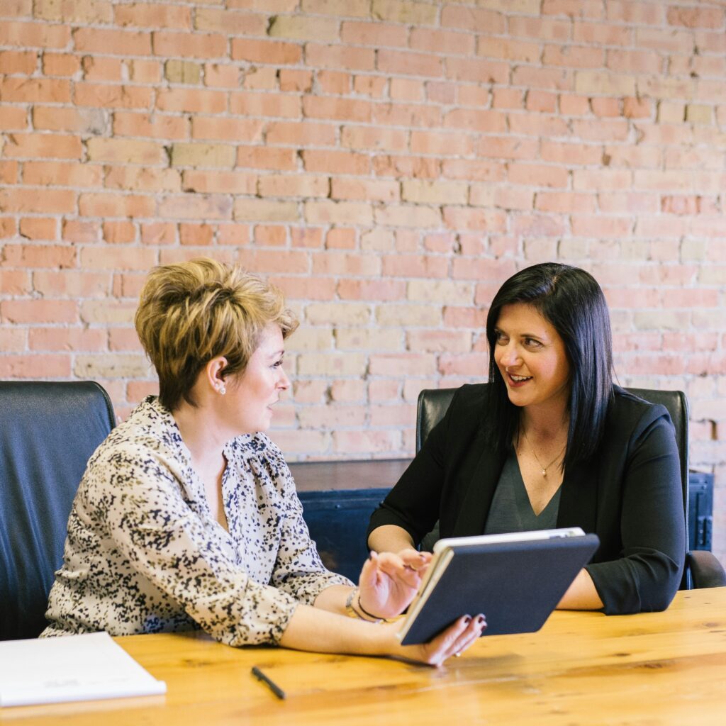 Two business women seated at a conference table, working together